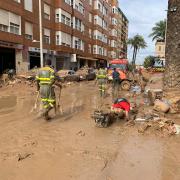 Traient fang d'un embornal amb una carmanyola de plàstic, a Paiporta