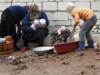 Diverses dones tenen cura dels seus fills i renten la roba en un camp de refugiats sirià, proper a la frontera amb Turquia Reuters