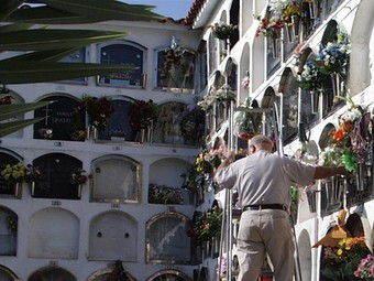 un home posa flors en un dels nínxols del cementiri de Premià de Mar. /  G.A