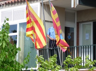 Un policia municipal lliga les banderes de l'Ajuntament a mitja asta.  M.C.B