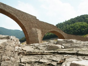 A l'esquerra, el pont de Querós, que queda a la vista quan hi ha sequera. A la dreta, imatges del poble i la vall abans de quedar negats pel pantà i en el moment de la inundació.  LLUÍS SERRAT / ARXIU HISTÒRIC COMARCAL DE LA SELVA