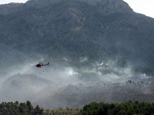 Un helicòpter bombarder sobrevola la zona de l'incendi hores abans de la tragèdia. EFE / JAUME SELLART