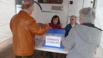 Dos ciutadans de Gallifa votant i detall de la pancarta a l'entrada del poble.  M.C.B