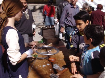 Alguns joves observen la tècnica del filferro en una parada del mercat.