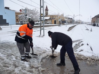 Dos homes traient la neu a pales al pas a nivell de l'estació de Tàrrega.  DAVID MARÍN