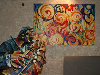 El saxofonista i un quadre de tema floral, a la mostra de l'obra de Morales, als Jardins de la Mercè. /  P.M