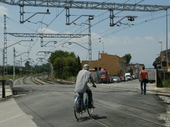 Un ciclista i un vianant travessen el pas a nivell de Flaçà que encara travessa el municipi. MIQUEL RUIZ
