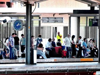Passatgers esperen un tren amb quasi una hora de retard a les andanes de l'estació de Girona ahir a migdia. JORDI SOLER