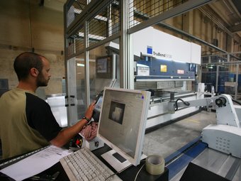 Uns treballadors controlen la plegadora de làser, la darrera màquina que ha adquirit l'empresa. LLUÍS SERRAT