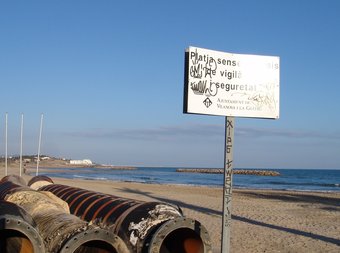 Platja de l'Ibersol, a Vilanova i la Geltrú, amb el rètol que indica que no hi ha servei de vigilància. CATI MORELL