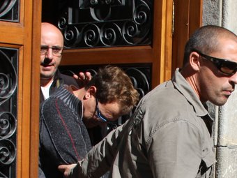 Joan Vila custodiat per dos mossos sortint detingut de la Caritat. ACN