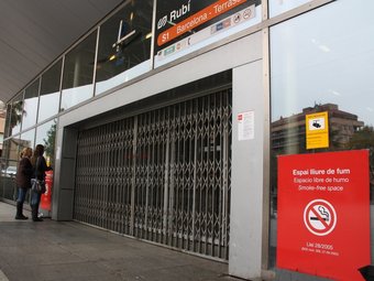 Dues usuàries llegeixen un cartell informatiu enganxat a la façana de l'estació tancada per la vaga ACN