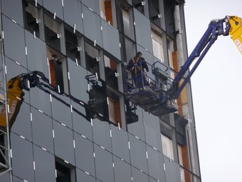 Un operari col·loca el vidre de la façana al seu forat. ESCORCOLL