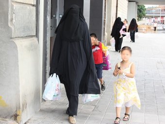 Tres dones musulmanes amb burca a Lleida, caminant amb menors per un carrer de la ciutat ACN