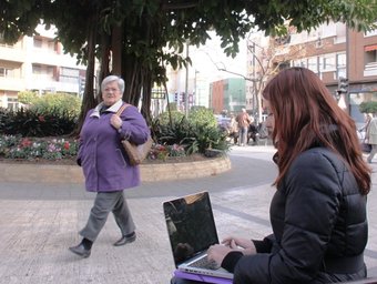 Una jove estudiant fa una consulta per Internet a la plaça del Canonge. CEDIDA