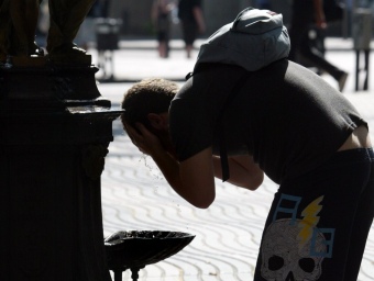 Un home es fa passar la calor refrescant-se amb aigua de la font de Canaletes, a Barcelona. A la capital catalana ahir es va posar a prova la prohibició d'anar amb el tors nu per la ciutat. QUIM PUIG