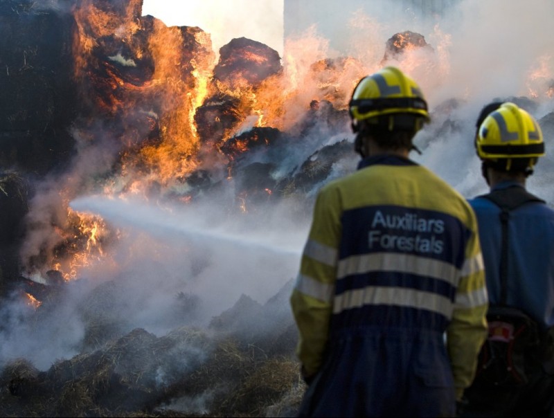 Un parell de bombers observen les flames del foc que va cremar ahir en una finca de Serra de Daró LLUÍS SERRAT