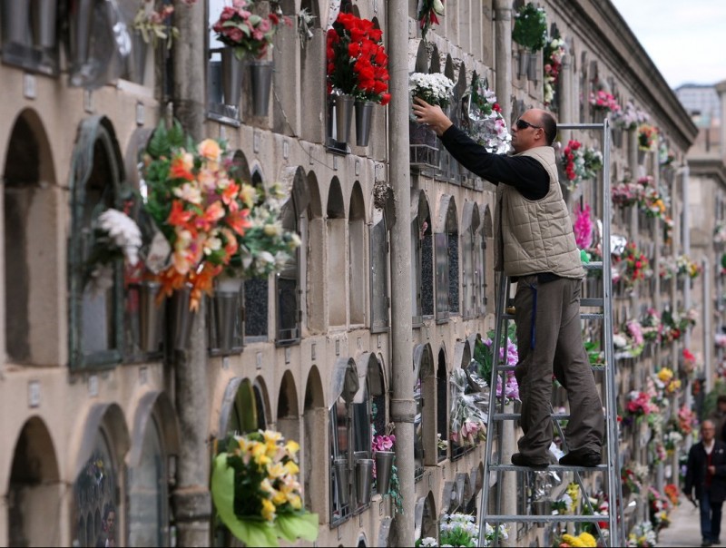 Un home posa flors al cementiri del Poble Nou