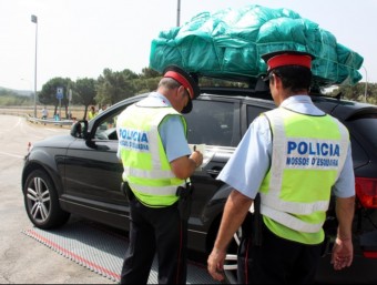 Dos mossos controlant ahir a la Jonquera un cotxe amb un gran embalum al sostre. MARINA LÓPEZ / ACN