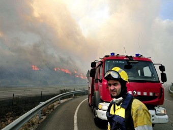 Un bomber i un camió del cos amb les flames al darrera seu a l'alçada de l'autopista AP-7 a la Jonquera ROBIN TOWNSEND
