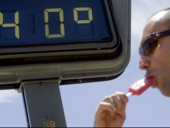 Un jove gaudeix d'un gelat sota un termòmetre que marca els 40 graus. ARXIU