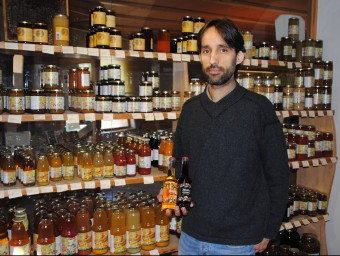 Rubén Valls, davant una mostra dels productes que ven l'empresa i ensenyant dues ampolles del nou suc amb bombolles.  J. TORT