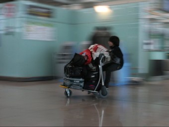 Un infant jugant a arrossegar un carretó per l'aeroport del Prat de Llobregat MARTA PÉREZ