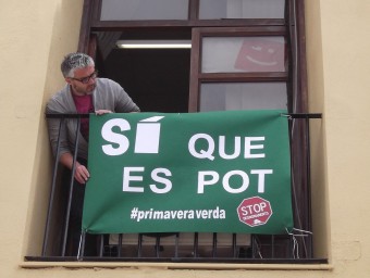 Juanma Ramon penja una pancarta a la balconada del despatx de Compromís. EL PUNT AVUI
