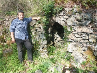 Llorenç Planagumà, fotografiat amb una cabana de pastor al Bosc de Tosca, feta amb pedra dels tossols volcànics formats fa 17.000 anys. J.C