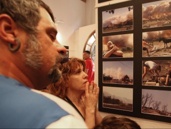 Uns veïns comenten les fotografies de l'exposició de fotografies dedicada als incendis de l'estiu passat i inaugurada ahir a Darnius LLUÍS SERRAT