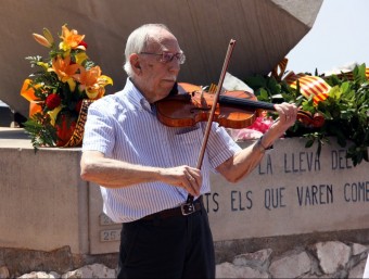 Un dels supervivents toca el violí davant el monument per la Pau. ACN