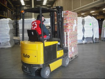 Un operari de la Creu Roja transporta aliments cap a l'interior del magatzem de l'organització. ACN