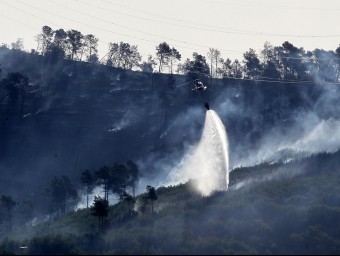 Un helicòpter remullant el bosc de Vallirana cremat la setmana passada AFP