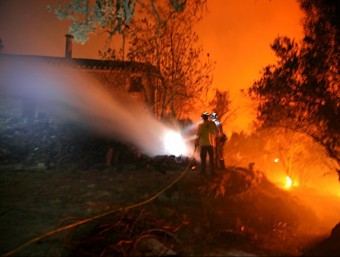 Dos bombers treballant en l'extinció de l'incendi en una masia dels Masos del Mig de Foixà JOAN CASTRO / ICONNA