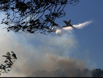 Una avioneta ruixant la zona afectada pel foc, aquest dimarts a la tarda MANEL LLADÓ