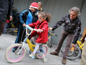 Una nena prova una de les bicicletes que l'ONG Bicicletes Sense Fronteres i BarcelonActua van entregar abans de Nadal al Raval de Barcelona QUIM PUIG