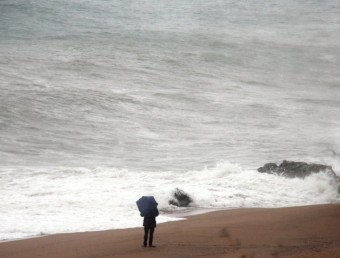 Una persona observa com trenquen les onades a Sant Pol de Mar ACN