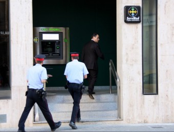 La comitiva judicial, amb el secretari al capdavant acompanyat per dos agents dels Mossos, entra a l'oficina de Caja Madrid (Bankia) el maig del 2013 ACN