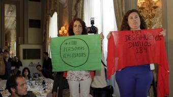 Dues activistes de la PAH mostren cartells contra els desnonaments durant la conferència de Miguel Arias Cañete, aquest divendres a l'Hotel Palace de Barcelona EFE