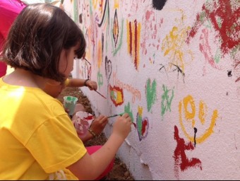 Unes joves participen en la pintada del mural de la Trobada. ESCOLA VALENCIANA
