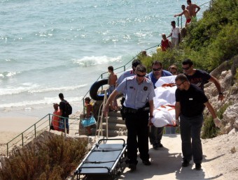 Els Mossos d'Esquadra i els treballadors de la funerària en el moment de retirar el cadàver de la dona morta a la platja Llarga de Salou ACN