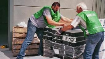 Voluntaris de l'ONG Banc de Recursos carregant torres d'ordinador que seran reutilitzades per alguna entitat social EL PUNT AVUI