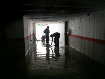 Bombers treballant en l'entrada a un pàrquing inundat a Palamós. JOAN CASTRO
