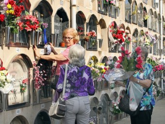 Unes senyores conversen mentre una neteja un nínxol ahir al cementiri de Poblenou EFE