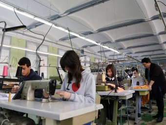 Un dels grups d'alumnes a les màquines de cosir de l'escola de teixits de Canet amb la professora, Carmen Lara. QUIM PUIG