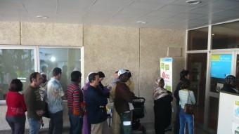 Un grup de persones, amb una presència important d'immigrants, fent cua en una oficina de Treball ANNA PUIG