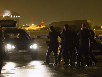 Imatge d'un dels fèretres transportat cap a un cotxe funerari després de l'arribada a l'aeroport del Prat ACN