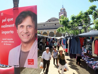 Un cartell electoral  del PSC i del seu candidat, Manel Roqueta, a la plaça Farners, ahir, dia de mercat a Santa Coloma QUIM PUIG