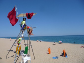 Dos socorristes a la platja de Pineda amb la bandera vermella que prohibeix el bany ahir a la tarda. T.M