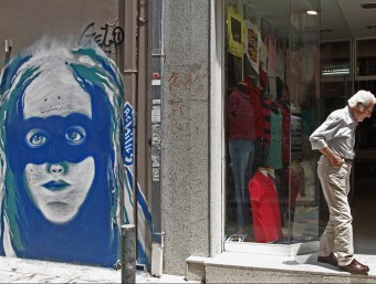 Un home passa aquest dimarts davant d'una botiga a Atenes EFE